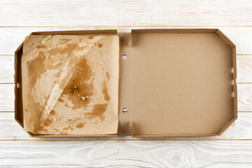 Empty pizza box with breadcrumbs on white wooden table flat lay view