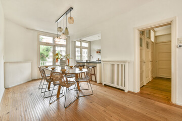 A stylish dining area featuring a wooden table surrounded by elegant chairs and natural light flooding through large windows, enhancing the minimalist aesthetic.