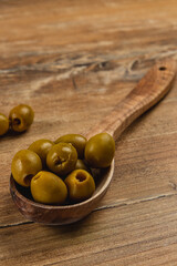 Fresh green olives in a wooden spoon on a rustic table setting