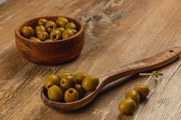 Olive varieties displayed on a wooden surface with a bowl and spoon