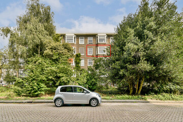 A contemporary building surrounded by lush greenery, showcasing a parked car in the foreground, ideal for urban aesthetics and architecture lovers.