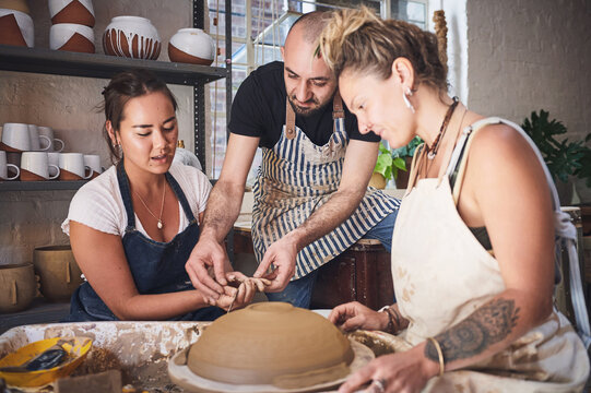 Teacher, learning and people in pottery workshop for clay molding, design process or shaping technique. Apprentice, class or potter with sculpture practice for handicraft, production or manufacturing
