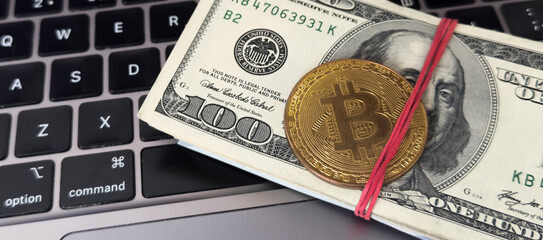 Golden bitcoin with dollar bills on computer keyboard
