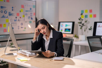 A woman in a business suit is sitting at a desk with a tablet in front of her