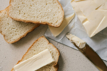 A close-up of a slice of bread with butter on a textured surface, sprinkled with coarse salt. A rustic and simple breakfast or snack setup with soft natural lighting and a warm atmosphere