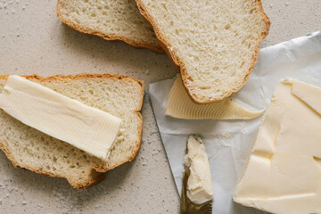 A fresh slice of bread with a thick layer of butter, a butter knife, and scattered salt on a textured surface. Simple and rustic food preparation, highlighting homemade breakfast or snack essentials
