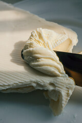 Close-up of a knife spreading fresh butter with soft curls forming on the blade. Warm natural light highlights the creamy texture, creating a rustic and appetizing food scene