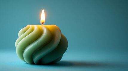 Swirled green candle burning against a teal background.