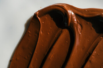 Close-up of smooth chocolate frosting with rich texture and deep brown color. The creamy, glossy surface has distinct swirls, highlighting its velvety consistency, perfect for cakes and desserts