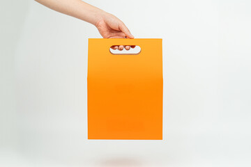 Minimalist Hand Holding Vibrant Orange Paper Bag