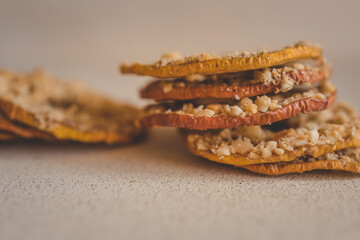 Stack of dried apple slices with crushed nuts on top. Healthy homemade fruit chips with nuts on light background. Natural organic snack, vegetarian food, diet dessert, close-up