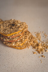 Stack of dried apple slices with crushed nuts on top. Healthy homemade fruit chips with nuts on light background. Natural organic snack, vegetarian food, diet dessert, close-up