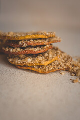 Stack of dried apple slices with crushed nuts on top. Healthy homemade fruit chips with nuts on light background. Natural organic snack, vegetarian food, diet dessert, close-up