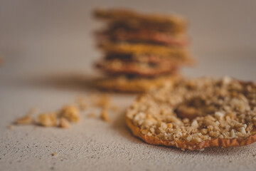 Round dried apple slice with crushed nuts on top. Healthy homemade fruit chips with nuts on light background. Organic vegetarian snack, diet dessert, close-up of natural sweet