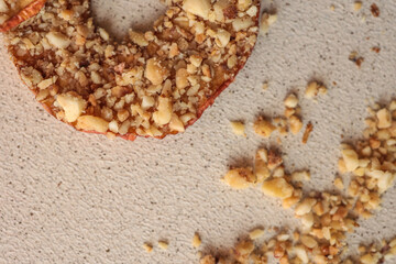 Stack of dried apple slices with crushed nuts on top. Healthy homemade fruit chips with nuts on light background. Natural organic snack, vegetarian food, diet dessert, close-up