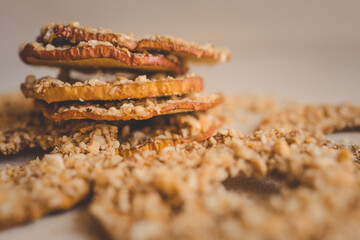 Stack of dried apple slices with crushed nuts on top. Healthy homemade fruit chips with nuts on light background. Natural organic snack, vegetarian food, diet dessert, close-up