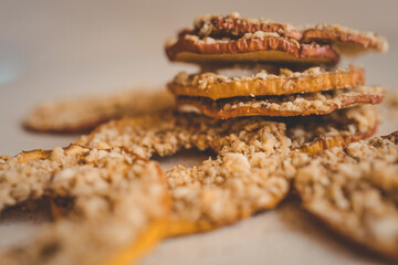 Stack of dried apple slices with crushed nuts on top. Healthy homemade fruit chips with nuts on light background. Natural organic snack, vegetarian food, diet dessert, close-up