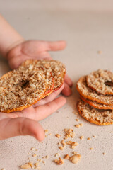 Child hand taking dried apple chip with crushed nuts. Healthy natural snack for kids, sweet fruit dessert with nuts. Organic sugar-free food for children. Close-up of hand and stack of chips