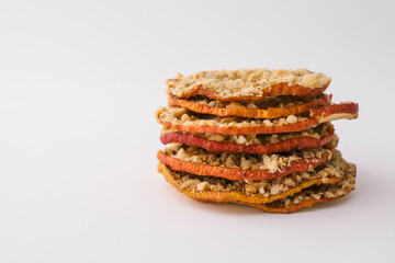 Stack of dried apple chips with chopped nuts on white background. Healthy vegan snack, organic diet food, crispy sweet apple slices, sugar-free dessert for children and adults