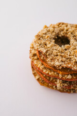Stack of dried apple chips with chopped nuts on white background. Healthy vegan snack, organic diet food, crispy sweet apple slices, sugar-free dessert for children and adults