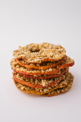 Stack of dried apple chips with chopped nuts on white background. Healthy vegan snack, organic diet food, crispy sweet apple slices, sugar-free dessert for children and adults
