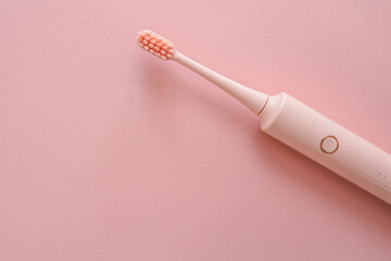 Pink electric toothbrush with soft bristles on pastel pink background. Minimalist and elegant oral...