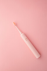 Pink electric toothbrush with soft bristles on pastel pink background. Minimalist and elegant oral...