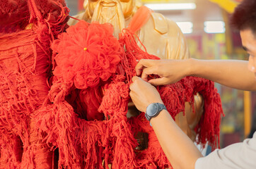 Male tourists praying and making a wish by tying red rope in a Chinese temple.