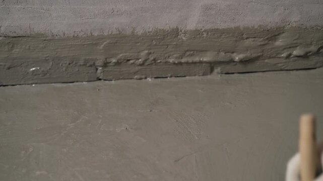 Construction worker applying waterproofing material on concrete floor
