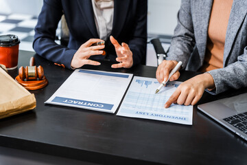 Two female lawyers in business suits meet at wooden desk, shaking hands over contract paper. wooden...