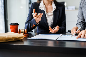 Two female lawyers in business suits meet at wooden desk, shaking hands over contract paper. wooden...