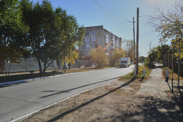Fototapeta premium Autumn landscape of a small town. Village houses and roads covered with orange foliage