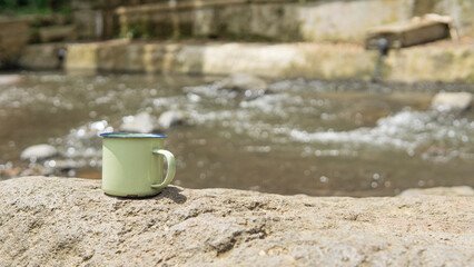 In the slow-flowing river, an old cup stands on a rock, adding beauty and tranquility to the scenery