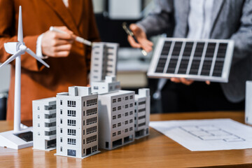 Two businesswomen sit at a desk in a meeting, discussing property development while building a...