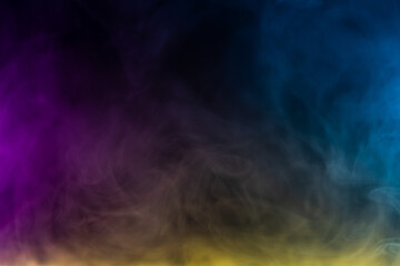 Blurred photo texture of colored smoke on a black background.