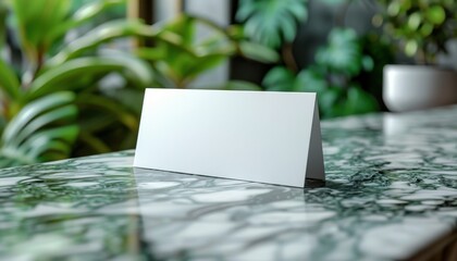 A white card is sitting on a table in front of a plant