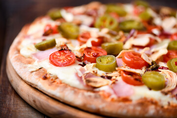 Pizza with ham, cherry tomatoes and mozzarella cheese. Wooden background. Soft focus. Close up.