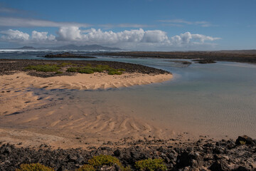 Caleta de arena blanca rodeada de rocas volcánicas en la costa norte de Fuerteventura, Islas Canarias. 