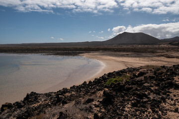 Caleta de arena blanca rodeada de rocas volcánicas en la costa norte de Fuerteventura, Islas Canarias. 