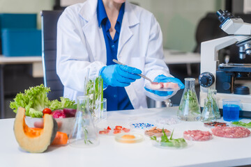 Middle-aged female laboratory worker wearing blue gloves conducts lab test on food ingredients...