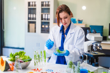 Middle-aged female laboratory worker wearing blue gloves conducts lab test on food ingredients...