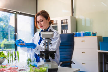Middle-aged female laboratory worker wearing blue gloves conducts lab test on food ingredients...