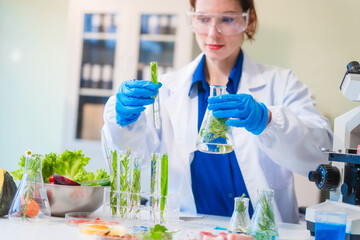Fototapeta premium Middle-aged female laboratory worker wearing blue gloves conducts lab test on food ingredients lettuce, cucumber, pork. Using microscope, she analyzes nutrients, preservatives, food safety records.