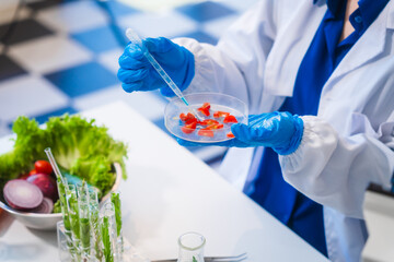 Middle-aged female laboratory worker wearing blue gloves conducts lab test on food ingredients...