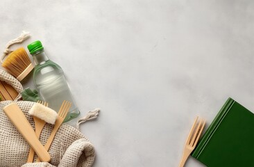 Eco-friendly kitchen items arranged on a light surface, including a water bottle, brushes, and wooden utensils, promoting sustainable living.