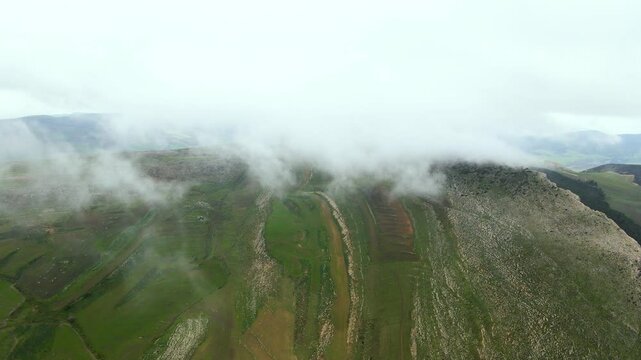 An aerial view of the mist-covered mountain peaks in Djebba, Beja. The clouds add a mystical touch to the rugged landscape, creating a serene and captivating scene.