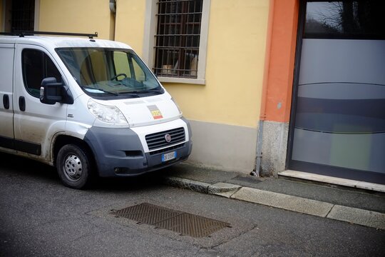 White Fiat Ducato van bearing STC logo parked beside vibrant yellow orange building in Cremona