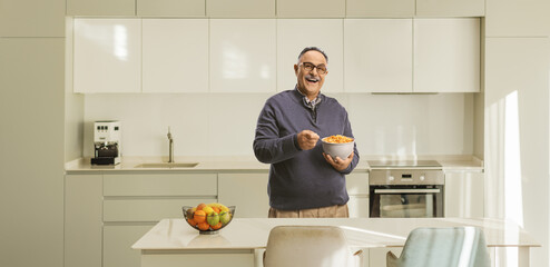 Smiling mature man holding a bowl of cereals