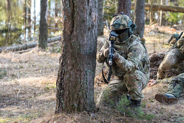 Soldiers in the forest. Military men in camouflage with weapons.