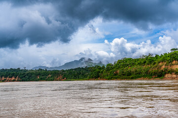Heavy rain over the Amazon River and forest, with a small boat navigating the water amidst the storm